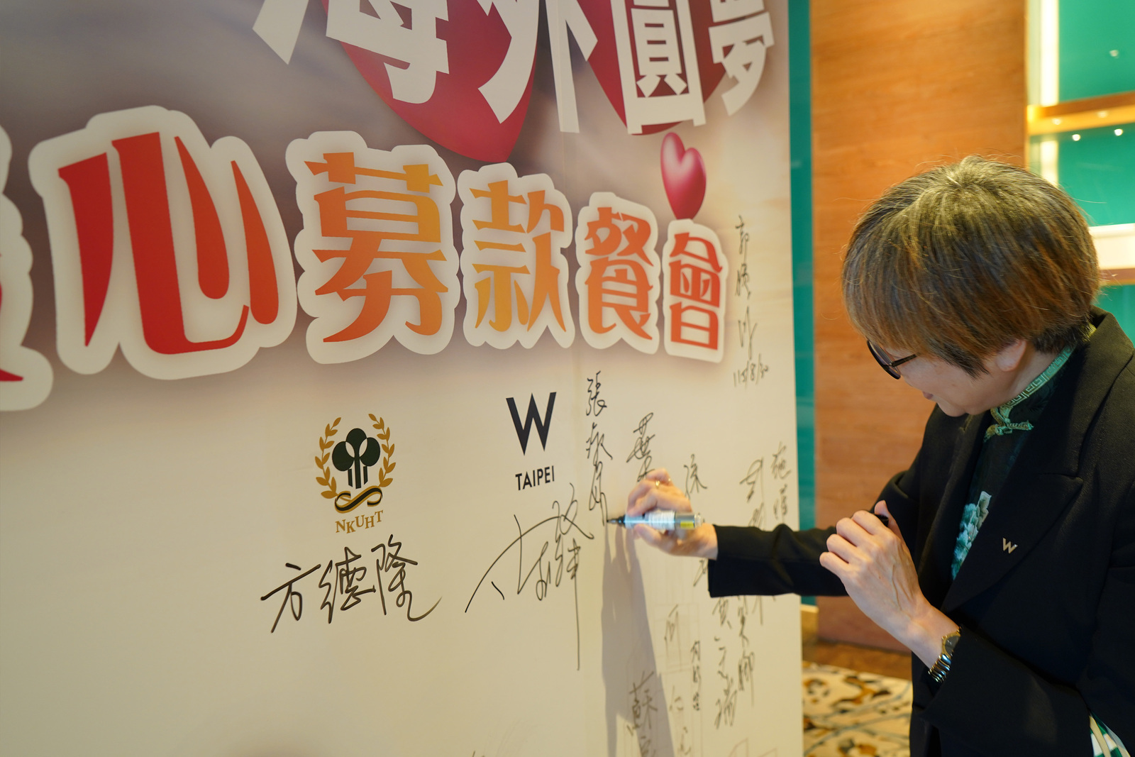 台北W飯店人資總監於募款活動背板簽名，以實際行動響應青年圓夢募款餐會，支持高餐大青年學子追逐夢想，為公益餐會注入溫暖力量