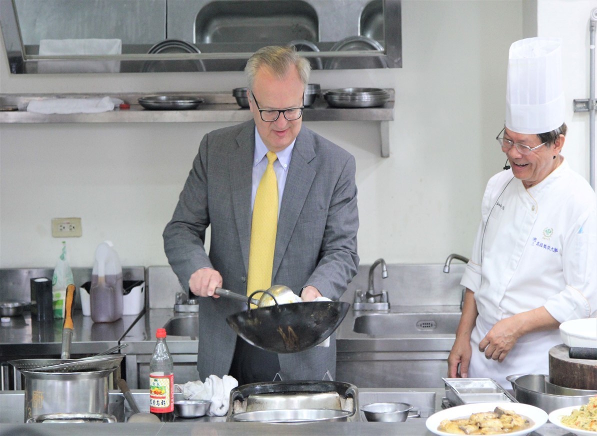 THE-ICE評鑑委員Andy Nazarechuck(左)進行國立高雄餐旅大學校園參訪時，向中餐廚藝系老師學習翻炒技巧。