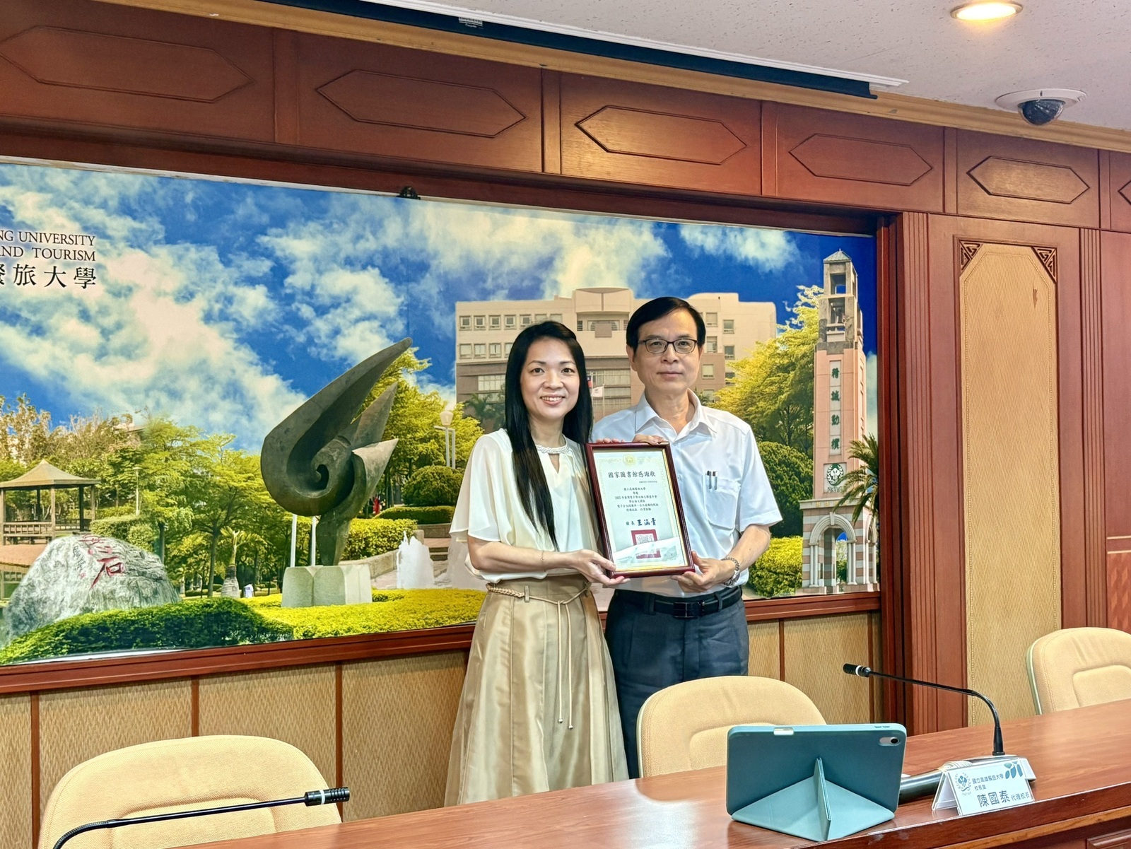 圖資長將此殊榮帶回高餐大，由陳國泰代理校長接過表彰圖片
